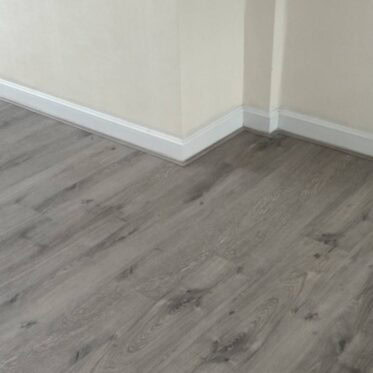 Smooth grey vinyl flooring in a modern residential interior with white baseboards.