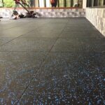 Interlocking black rubber flooring with blue speckles for outdoor or indoor use.