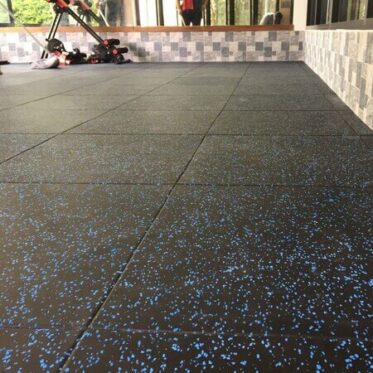 Interlocking black rubber flooring with blue speckles for outdoor or indoor use.