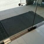 Non-slip rubber mat at doorway entrance in a commercial building for safety and cleanliness.
