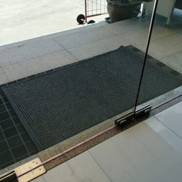 Non-slip rubber mat at doorway entrance in a commercial building for safety and cleanliness.