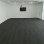 Smooth dark grey carpet flooring in modern office room with white walls and ceiling lighting.
