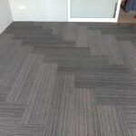 Glossy grey carpet tiles with striped pattern for office or condo flooring.