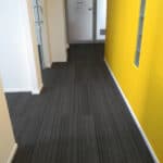 Modern dark carpet flooring in a commercial or office space with colourful yellow walls.
