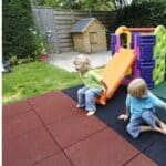 Colorful playground slide on outdoor rubber flooring with children playing, ideal for playgrounds and outdoor activity areas.