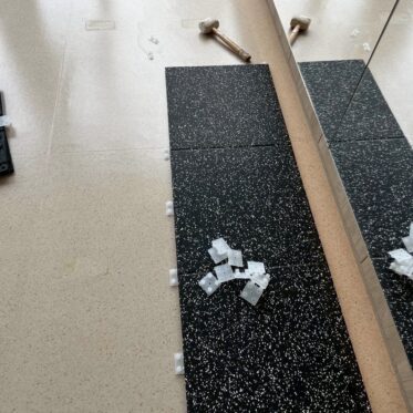 Black speckled vinyl flooring installation in an indoor space.