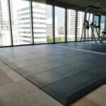 High-quality tile flooring in a modern gym with large windows and city view.