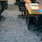 Colourful patterned office carpet with chairs and desks in a modern workspace setting.