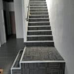 Stylish stairway with modern striped flooring and matching carpeting in a contemporary interior.