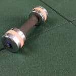 Rubber fitness dumbbell on gym flooring, strength training equipment.