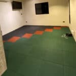 Colorful interlocking flooring tiles in a modern indoor space with a small wall-mounted TV and window.