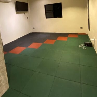 Colorful interlocking flooring tiles in a modern indoor space with a small wall-mounted TV and window.
