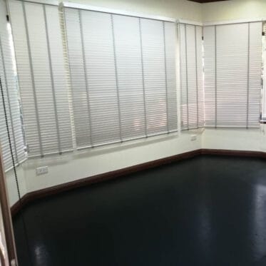 Blinds installed in an office room with white horizontal window blinds for privacy and light control.
