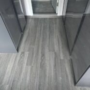Shiny grey laminate flooring in a modern kitchen or laundry area.