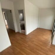 Shiny wooden flooring installed in a modern condo room with white walls and large windows.