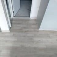 Smooth grey laminate flooring in a modern apartment hallway.