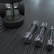Dumbbells on black rubber gym flooring in fitness centre.